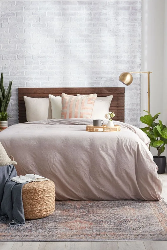 Warm moody winter bedroom retreat with dark walnut headboard, heavy Belgian linen drapery, layered down bedding, and soft 2400K bedside reading sconces
