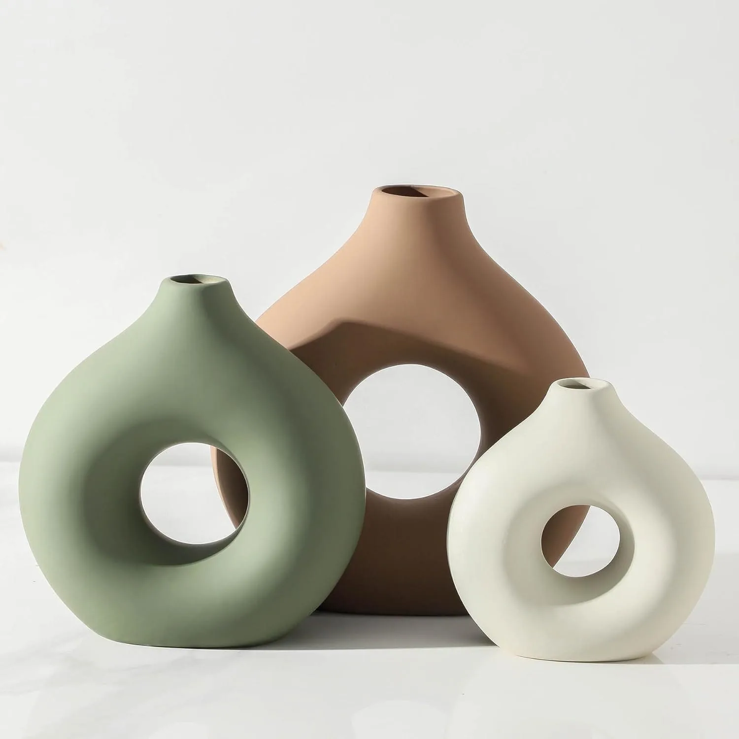 An earthy ceramic vase set in sage green, terracotta brown, and cream styled on a bright shelf with soft neutral minimalist decor.